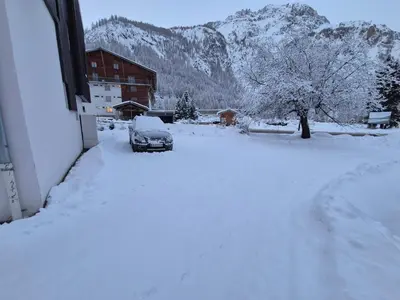 L'établissement Le Nid Douillé du Crêt, parking et terrasse en hiver